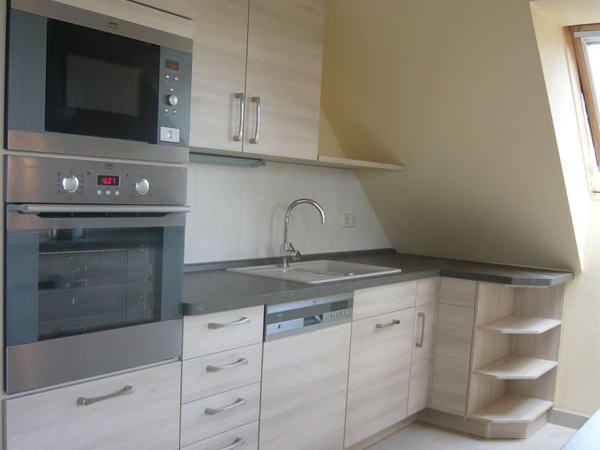 Eine kleine, funktionale Dachgeschossküche in hellem Holzdekor mit Edelstahlgeräten. Küchenstudio Pfarsky Hoyerswerda.